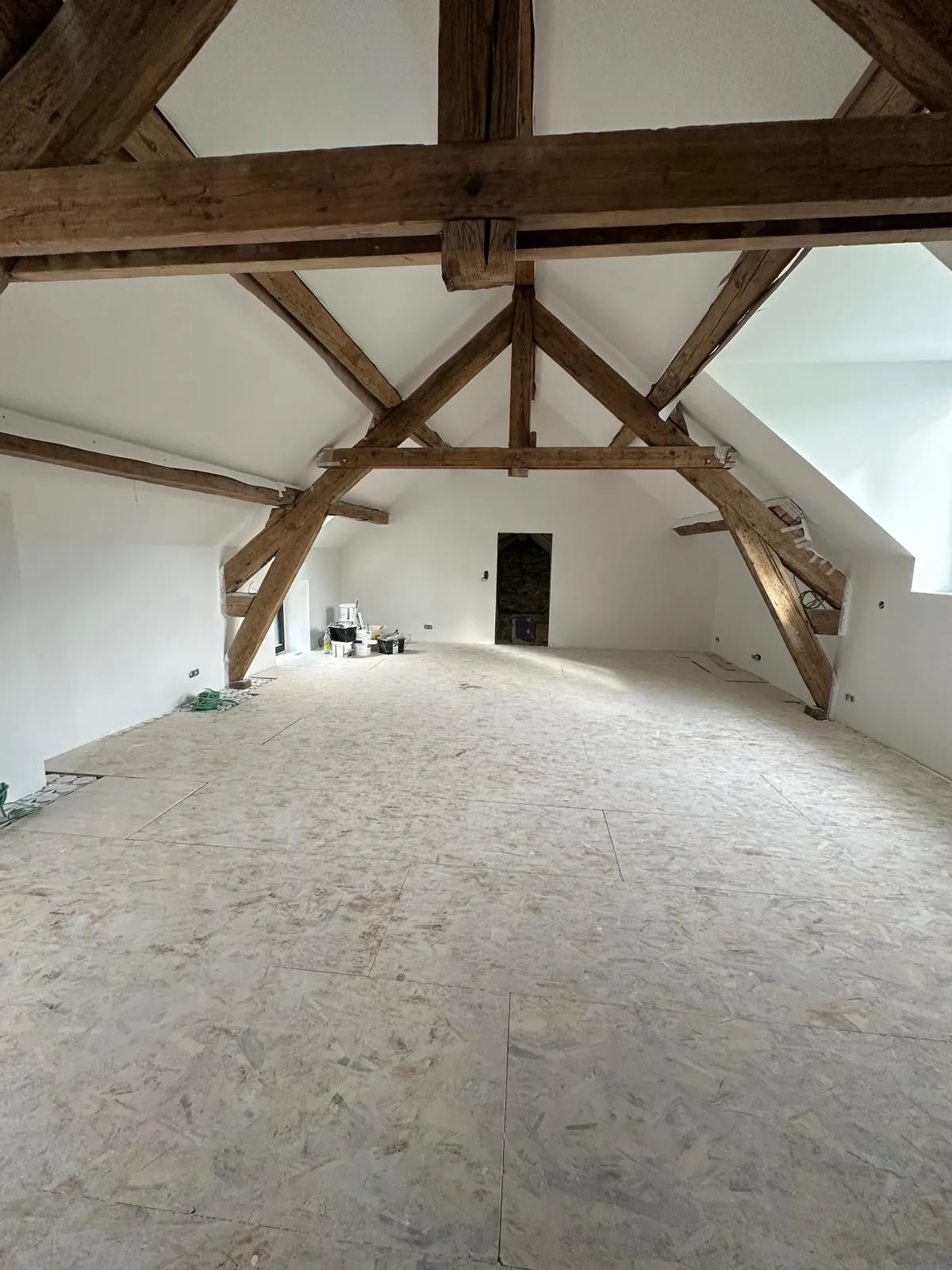 Combles rénovés sous une charpente en bois apparente