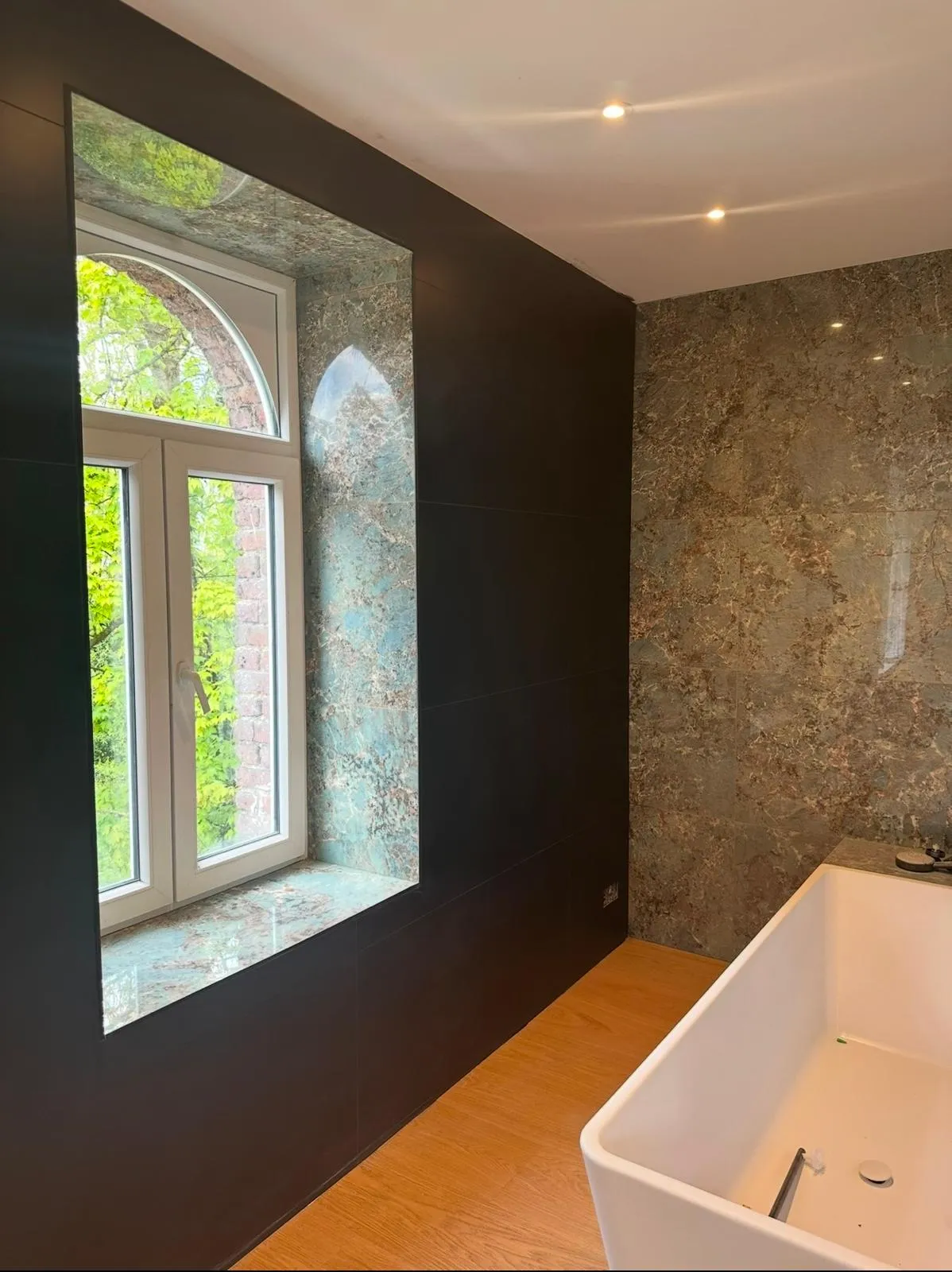 Salle de bain en marbre avec baignoire îlot et fenêtre cintrée